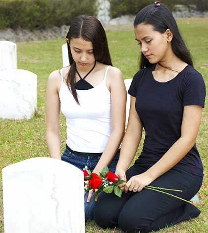 two girls sitting near a grave mourning the loss of a loved one