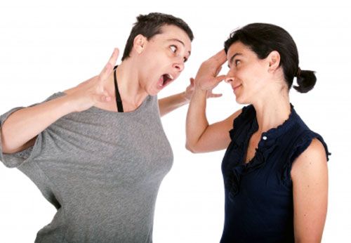 Woman smiling and trying to deal with anger as other gets angry