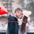 A couple in love standing close with nose touching and red heart balloons in hand