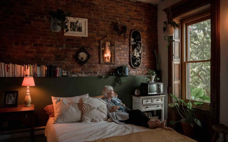 Senior woman sitting on bed in her home