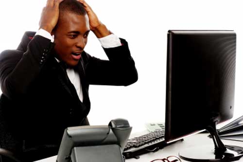 A black blogger holding his head viewing blog on desktop