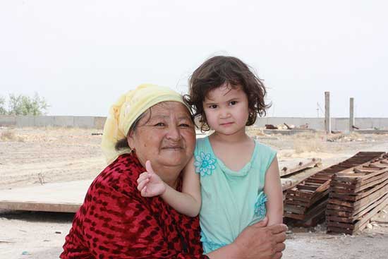 Grandchild standing with grandmother