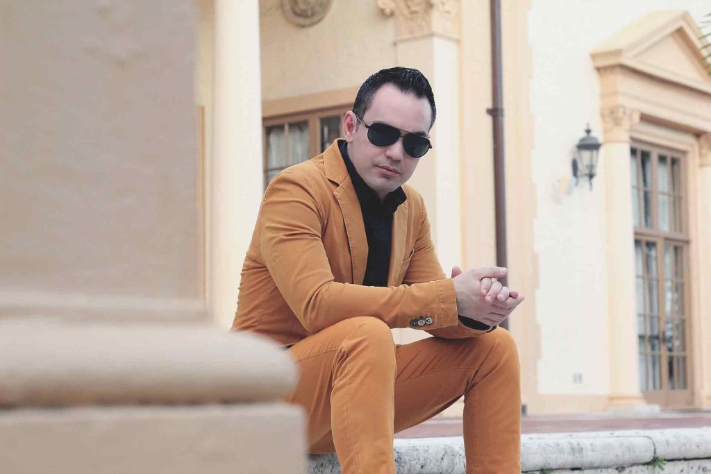 Man dressed in mustard fashion suit sitting on the stairs.