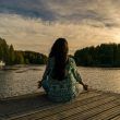 Woman meditating near lake to treat her depression