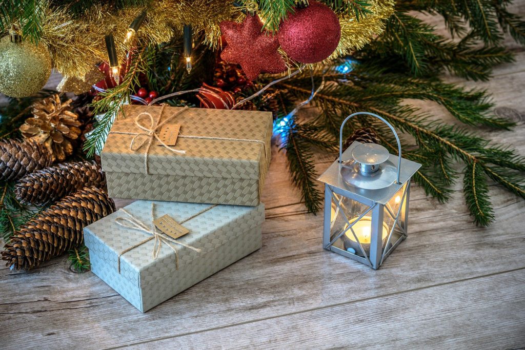 Gifts, lantern, and Christmas tree with decorations on the floor
