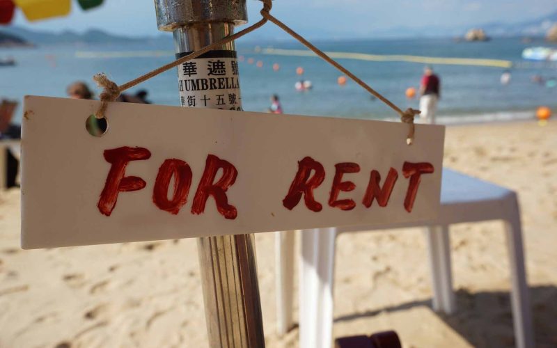 A for rent sign on an umbrella at a beach