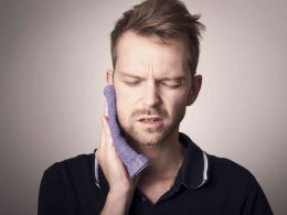 Man having problem with gum tooth and pressing a towel from outside