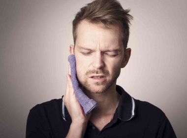 Man having problem with gum tooth and pressing a towel from outside