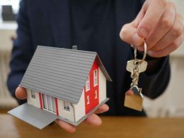 A man with a model of home and a key in hands for renting