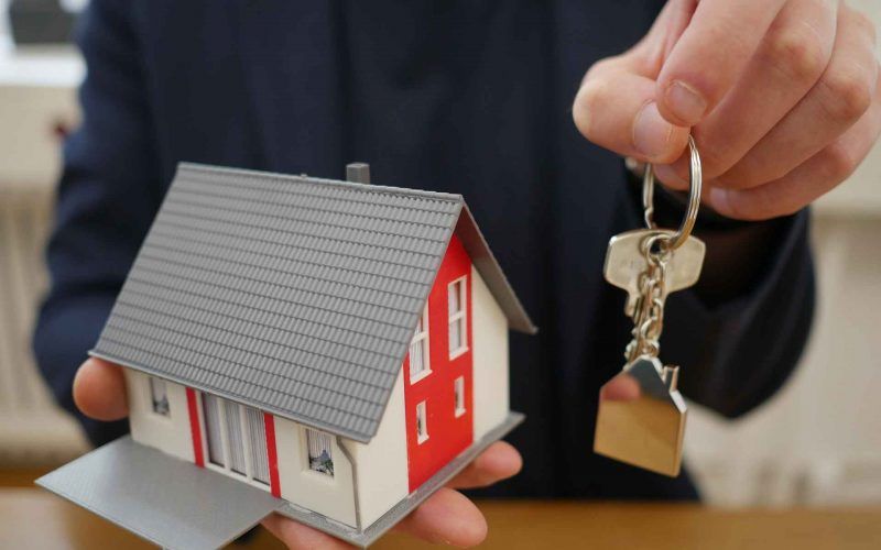 A man with a model of home and a key in hands for renting