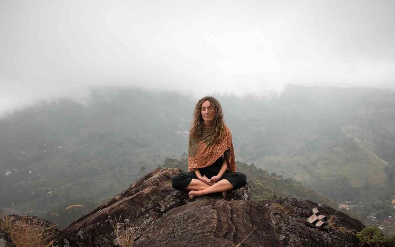 Woman on top of mountain in meditation as mindful practice