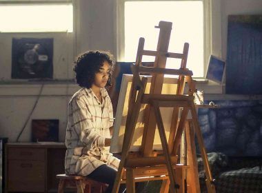 A girl painting on a canvas placed on an easel as a hobby
