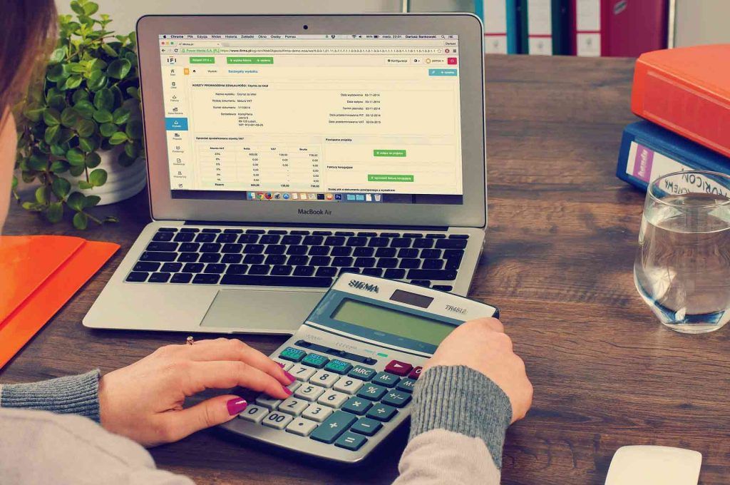 Woman managing business finances doing bookkeeping on laptop and calculator