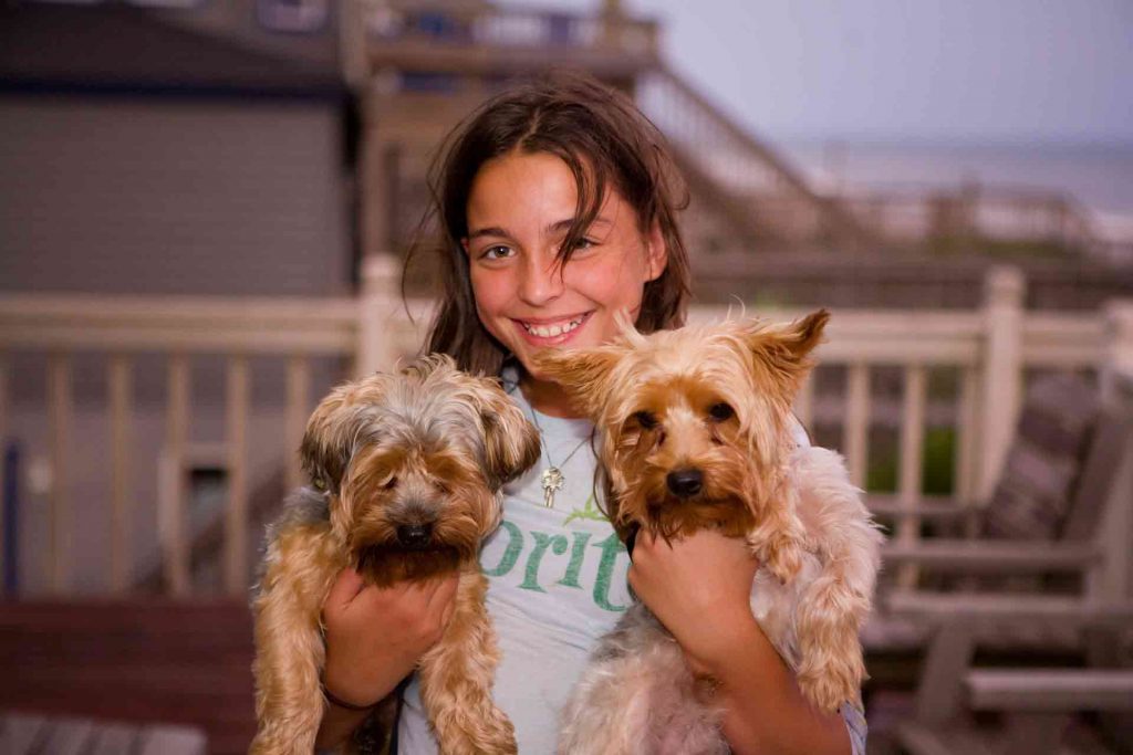 A pet parent woman with two puppies in hand