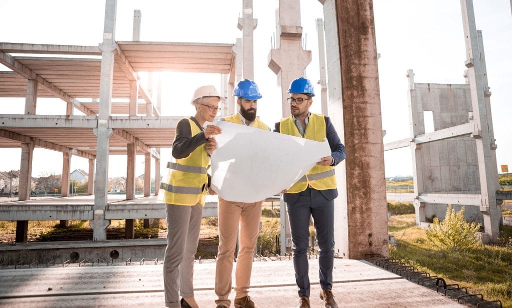 Three construction workers checking a map on a construction site