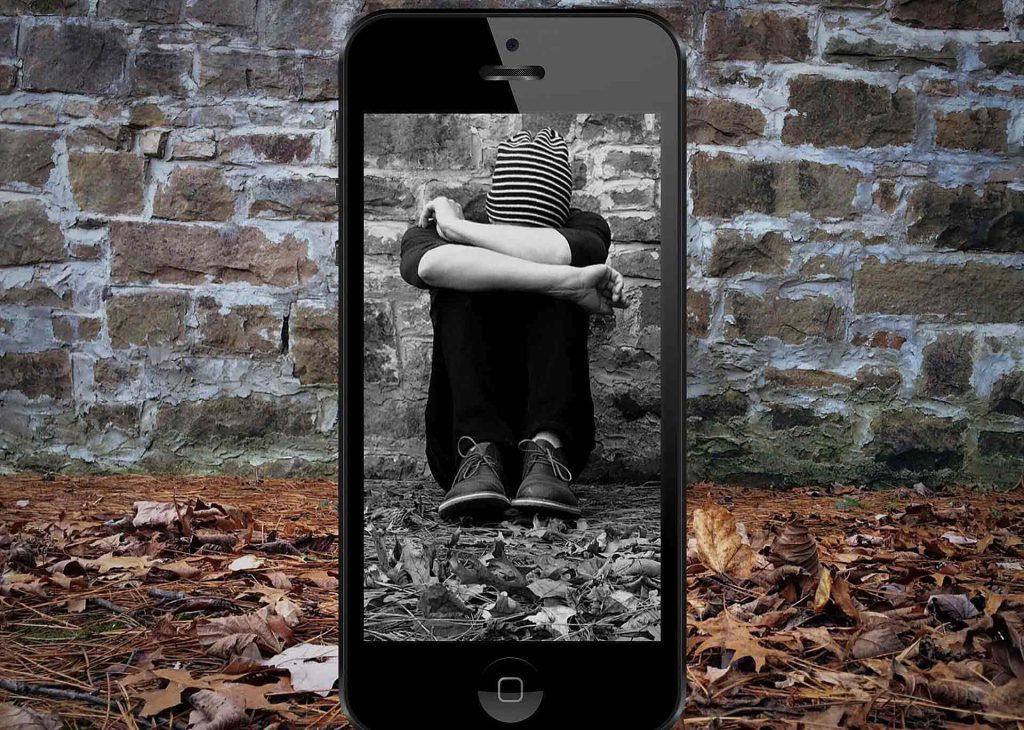 A teen sitting heads down against a wall within a mobile frame