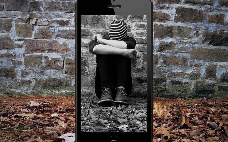 A teen sitting heads down against a wall within a mobile frame