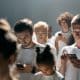 Teens standing in a group and engrossed in their mobiles.