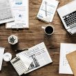 A laptop, coffee cup, and business expansion plan papers on a table.