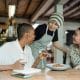 Happy customers at a table in a restaurant attended by a waiter